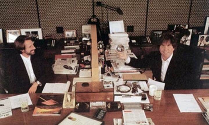 Photo of Hollywood superproducers Jerry Bruckheimer and Don Simpson with matching desks and suits.