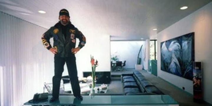 Photo of Hollywood superproducer standing on his glass-topped coffee table.