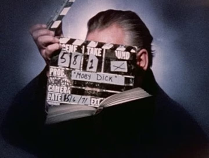 Photo of Orson Welles lost behind a clapper board.